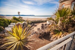 Une terrasse en bois, dotée de mobilier d’extérieur, qui offre une vue sur la plage.