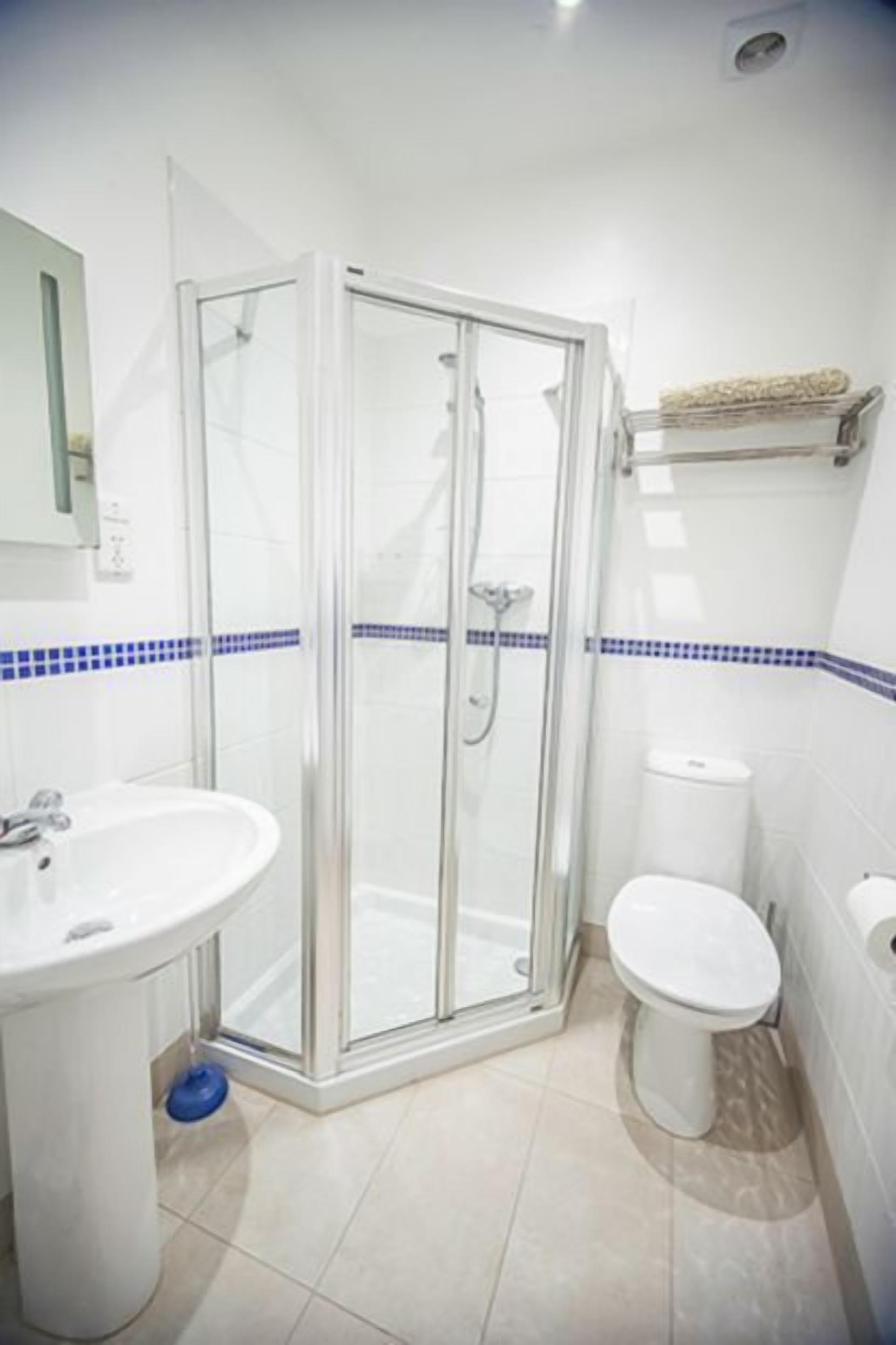 A bathroom with a glass shower enclosure, a sink, and a toilet.