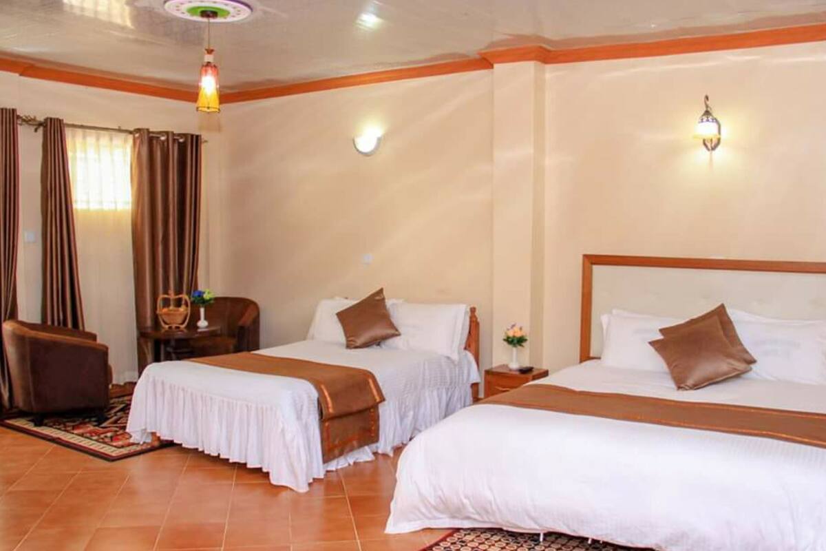 Habitación de hotel con dos camas, un escritorio, una silla y una lámpara decorativa.