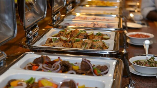 Un buffet proposant divers plats, notamment de la viande et des légumes.
