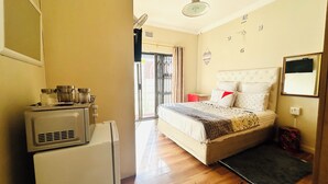 Ein kleines Hotelzimmer mit Bett, einer Küchenzeile, einem Deckenventilator und Blick durch eine Tür.