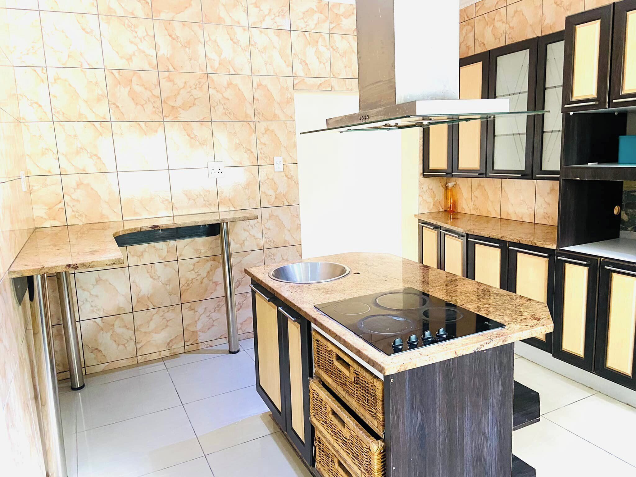 A modern kitchen with marble tiles, stainless steel appliances, and dark cabinetry.