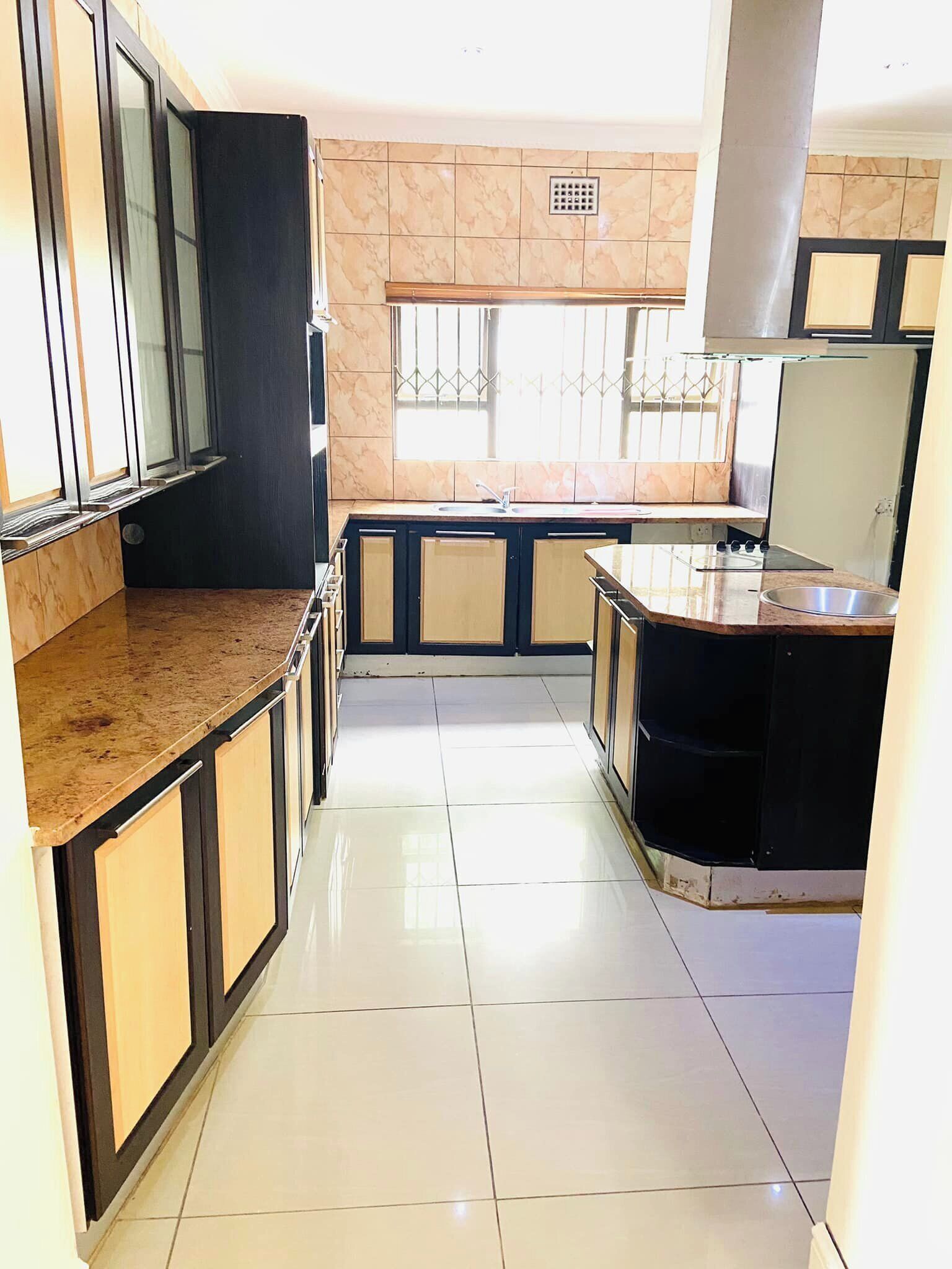 A kitchen with a central island, a window with bars, and cabinets with a two-tone design.