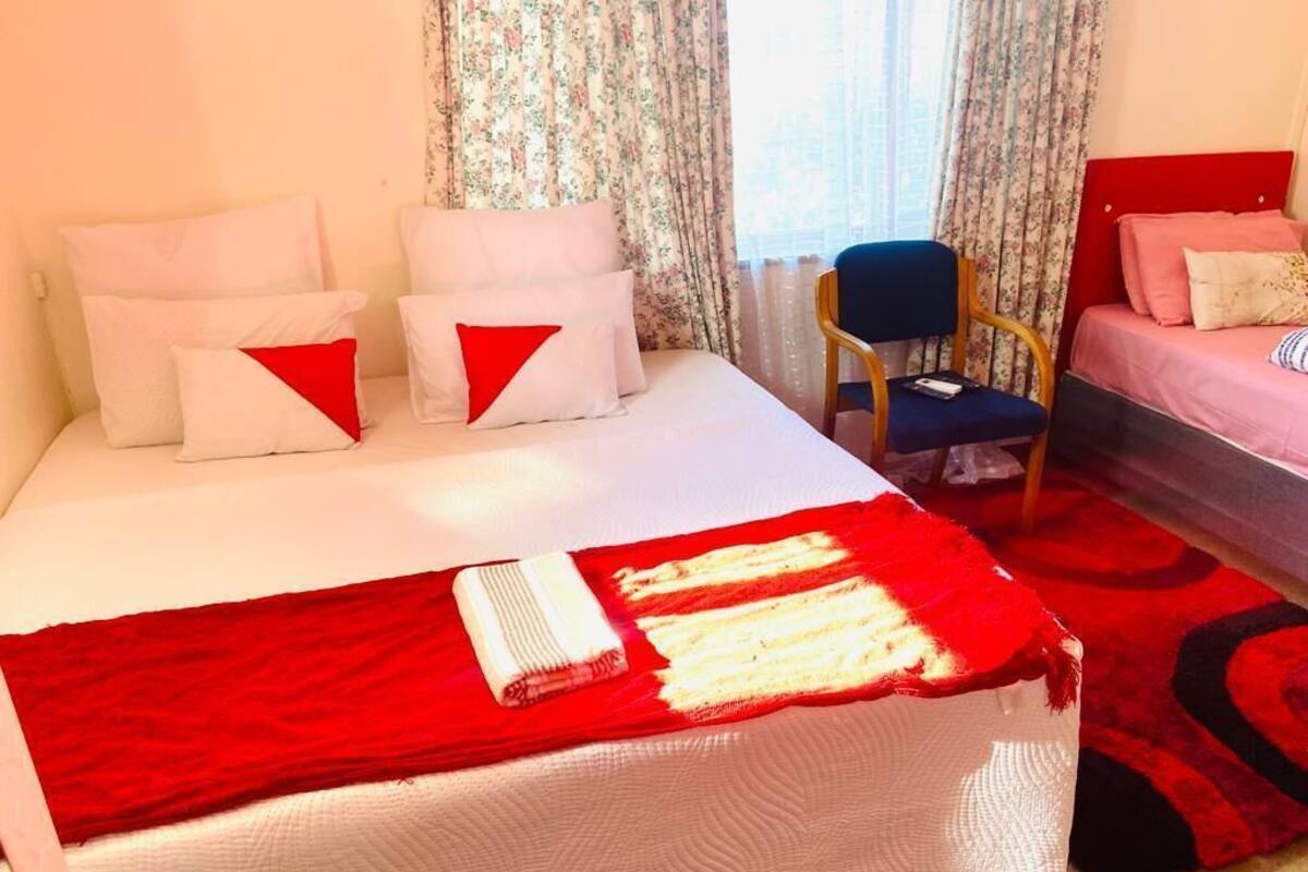 Una habitación de hotel con una cama, una silla y una manta a rayas rojas y blancas.