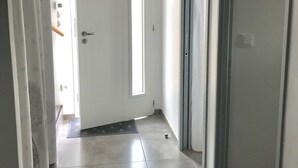 Un pasillo con una puerta blanca, un ventanal y una puerta con manija.