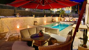 A poolside area with a red umbrella, lounge chairs, a round table, and a cactus plant. - HOLIDAY HOME "U SCRUSCIU RO MARI" (Avola)
