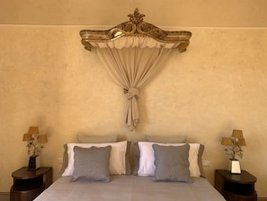 Un lit à baldaquin, deux tables de chevet avec des lampes et un mur au revêtement texturé.