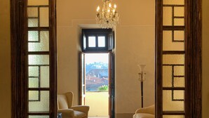 A spacious room with a wooden floor, two beige armchairs, a chandelier, and a view through a window with a wooden frame. - DUOMO, MEDIEVAL TOWER Florence: SANTA CROCE in the DONATI TOWER 4th floor w/lift (Firenze)