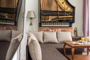 Ein Zimmer mit einem Flügel, einem Sofa und einem Tisch mit Frühstück.