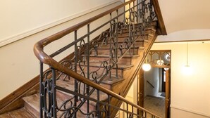 A wooden staircase with ornate metal railings and a wooden handrail. - Apartments Wygoda A4You (Kraków)