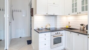 A kitchen with white cabinets, a black countertop, a stove, and a sink. - Apartments Wygoda A4You (Kraków)