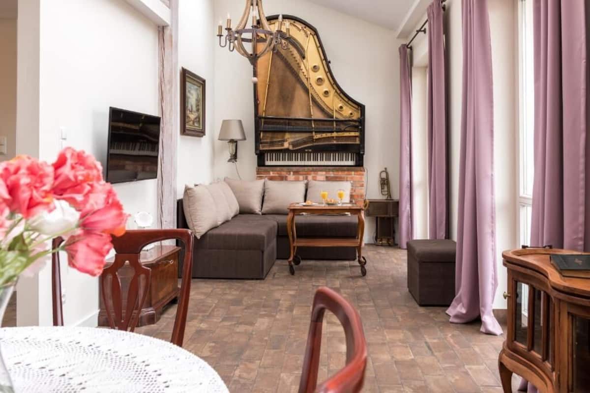 A living room with a grand piano, a sofa, a coffee table, and a dining area with chairs and a table.