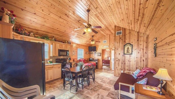 A log cabin interior with a dining area, kitchen, and living space. - RR 9122WC Wine Cup Cabin (New Braunfels)