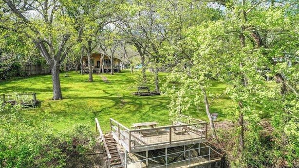 A rustic cabin with a wooden deck and a small bridge over a stream. - RR 9084BC Bluebonnet Cabin (New Braunfels)