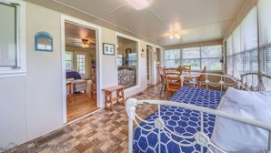 A room with a bed, a dining table, chairs, a small kitchen area, and a view through the window. - RR 9084BC Bluebonnet Cabin (New Braunfels)