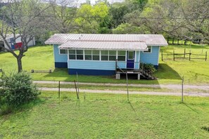 Un petit bâtiment d’un seul étage, à l’extérieur bleu et doté d’un toit en métal, entouré d’une pelouse et d’arbres.