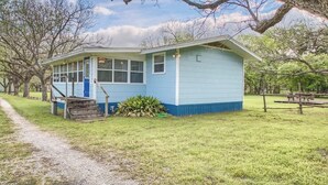 A small, single-story building with a porch and a staircase leading to the entrance. - RR 9084BC Bluebonnet Cabin (New Braunfels)
