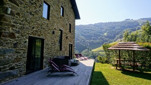 A stone building with a deck, outdoor seating, and a view of a valley. - Charming gîte with SPA / Jacuzzi Lodge in the Basque Country (VALCARLOS)