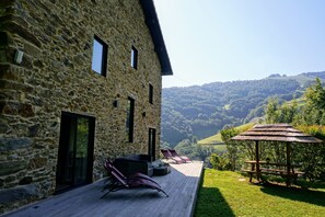 A stone building with a deck, outdoor seating, and a view of a valley. - Charming gîte with SPA / Jacuzzi Lodge in the Basque Country (VALCARLOS)
