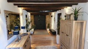 A hallway with wooden beams, a bench, potted plants, and a door at the end. - Charming gîte with SPA / Jacuzzi Lodge in the Basque Country (VALCARLOS)