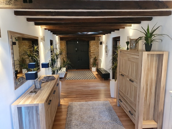 A hallway with wooden beams, a bench, potted plants, and a door at the end. - Charming gîte with SPA / Jacuzzi Lodge in the Basque Country (VALCARLOS)