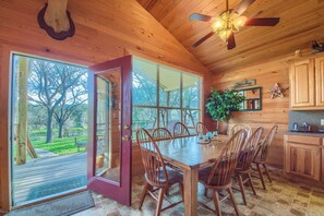 Enjoy meals in this dining area with a large table and six chairs, surrounded by a beautiful view of the lawn and trees.