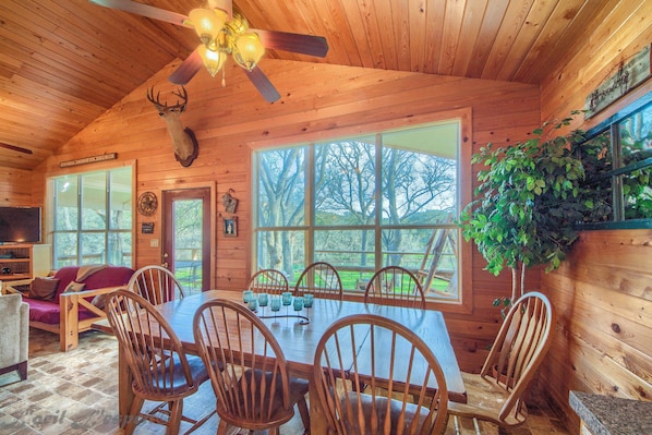 Enjoy family meals and gatherings in the cabin's dining area with a large table and six chairs, complemented by a comfortable sofa and TV.