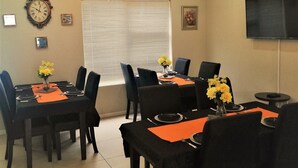 A dining area with a chandelier, a clock, and a television on the wall. - Azinnia Rivonia Guest House (Sandton)