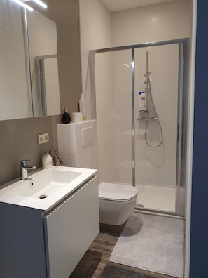 A modern bathroom with a white sink, toilet, and shower.