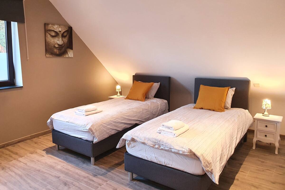 Un dormitorio con dos camas, cada una con cabecera, mesita de noche y lámpara de pared.