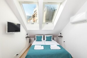 A bedroom with a bed, two windows, a TV, and an air conditioner. - Apartments Starowiślna 54  A4You (Kraków)