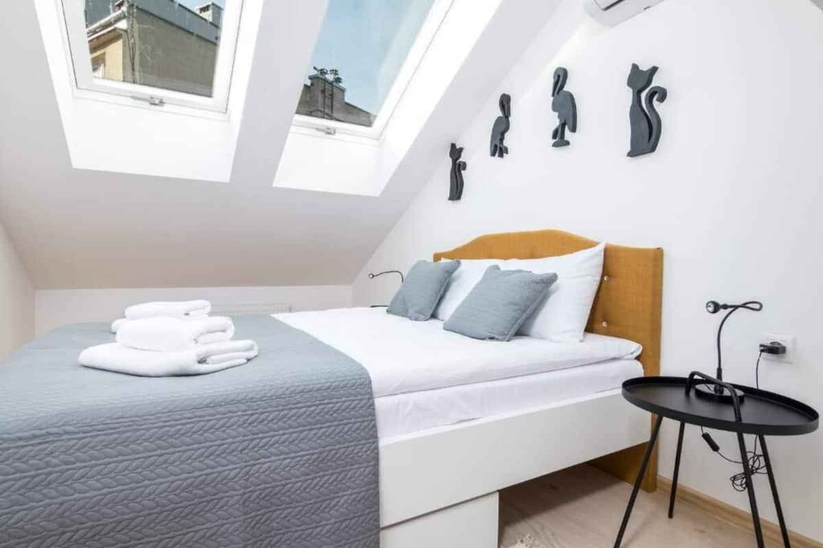 Ein Schlafzimmer mit Bett, einem kleinen Tisch, einer Wand-Klimaanlage und einem Oberlicht.