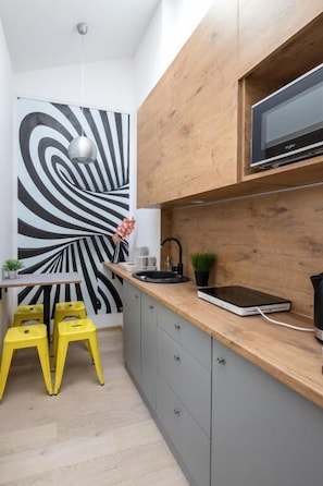 Cozinha moderna com bancada de madeira, micro-ondas preto e uma grande obra de arte abstrata em preto e branco.