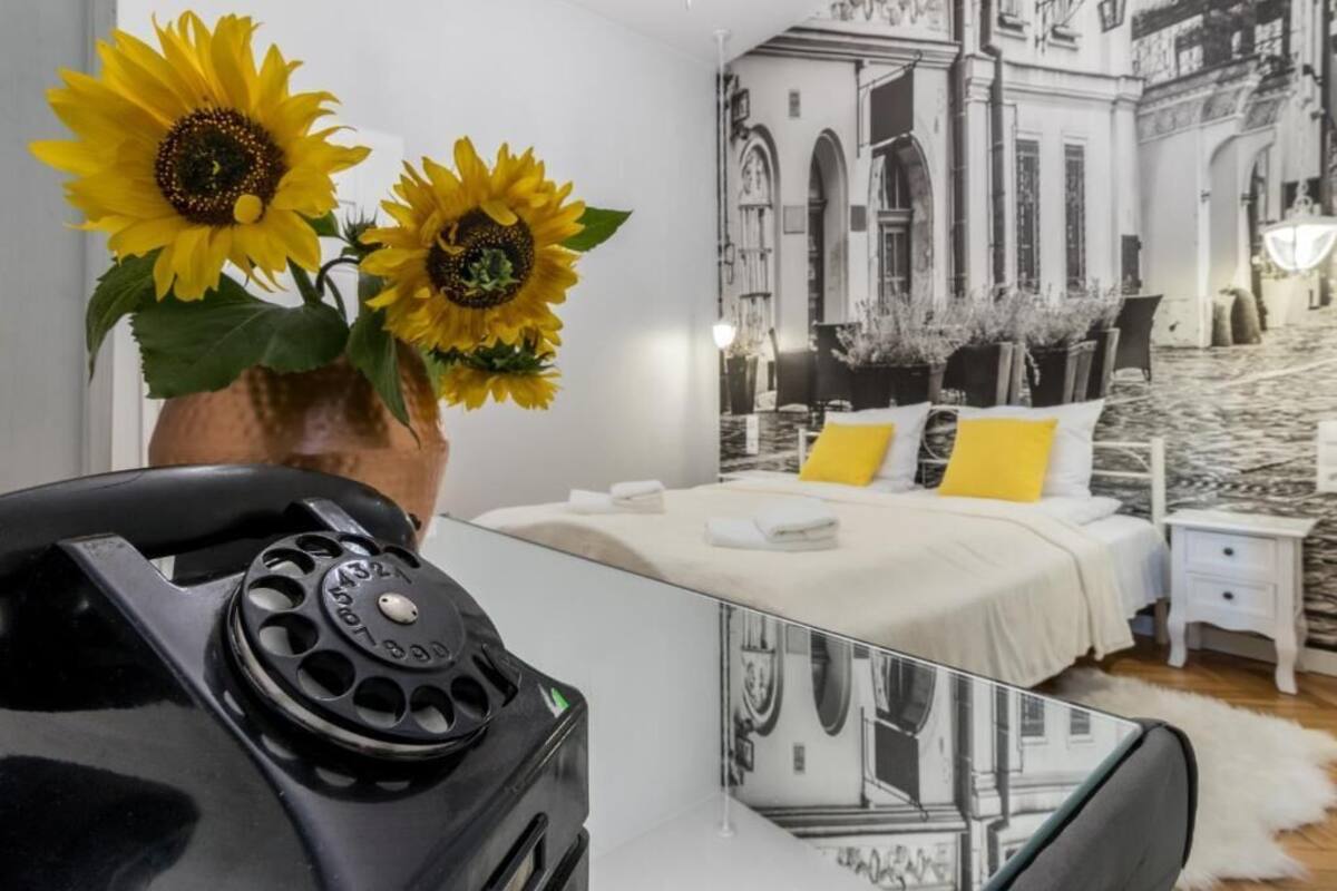 Ein Schlafzimmer mit einem Bett, Nachttischen, einer Vase mit Sonnenblumen und einem schwarzen Telefon.