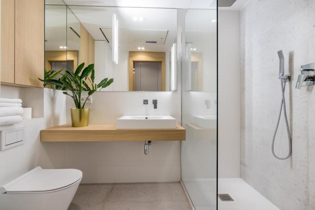 A modern bathroom with a white sink, a toilet, and a shower.