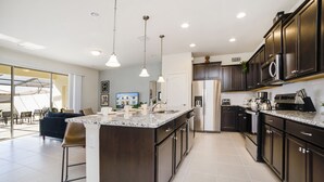 Una cocina moderna con armarios oscuros, una isla central e iluminación colgante.