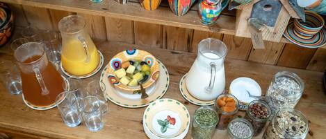 A wooden table with various glass jars containing grains and seeds, a pitcher of milk, and a fruit bowl.