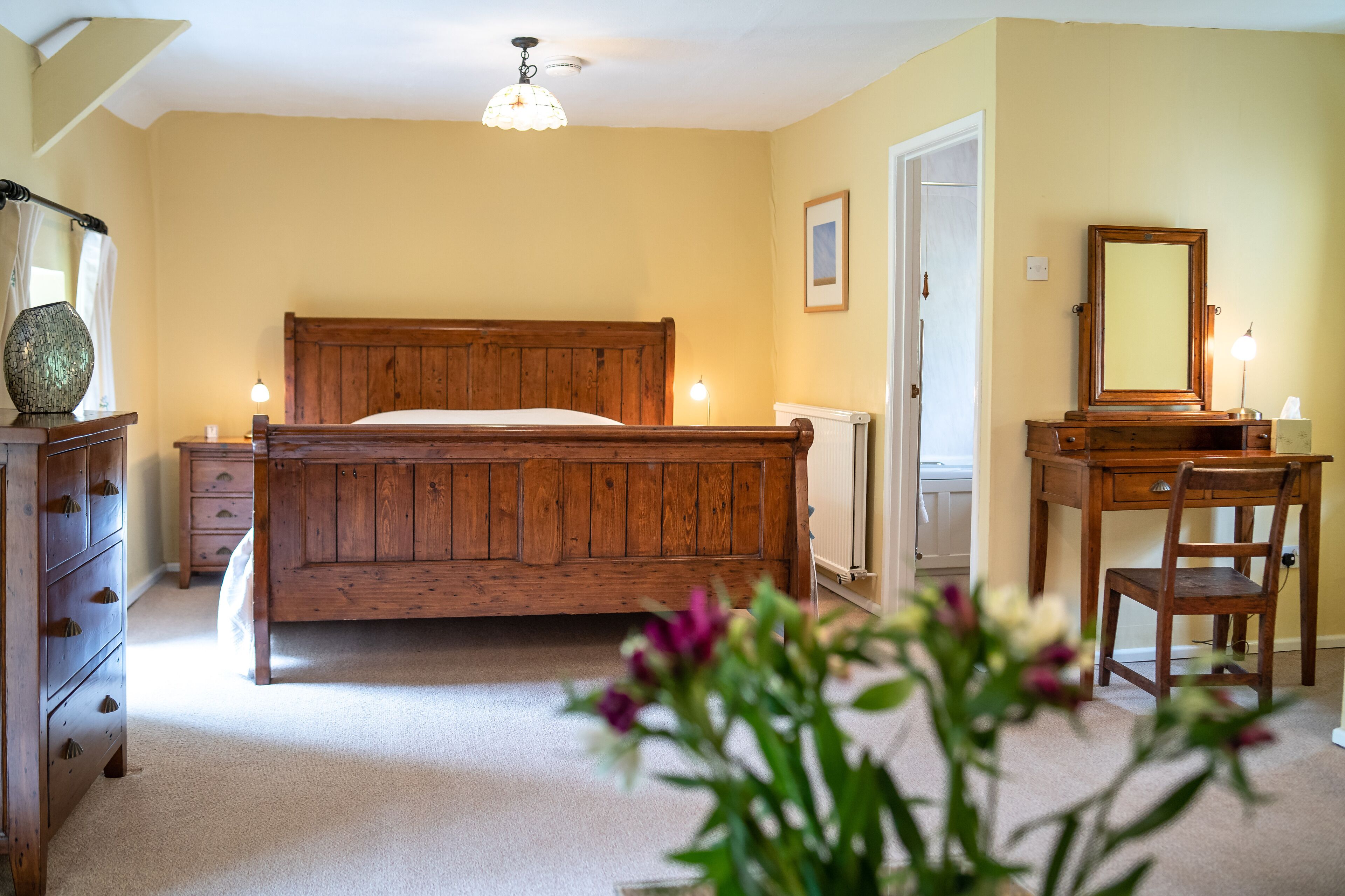 Un dormitorio con una cama de madera, un aparador, una silla y un escritorio.