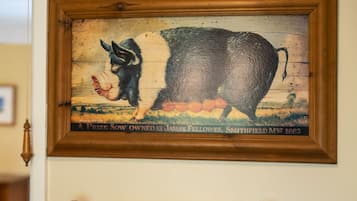 A framed picture of a pig and a dog on a wall, a towel rack with two towels, and a wooden door.
