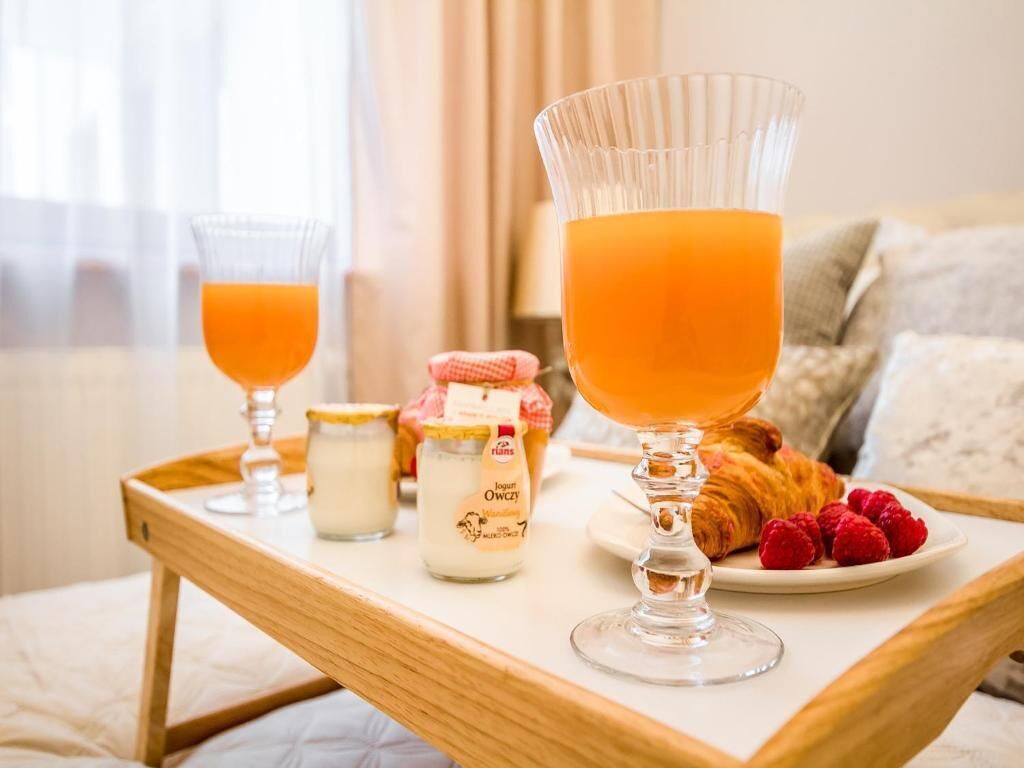 Egy reggelit tartalmazó tálca, rajta egy pohár narancslé, egy kis tejszínnel teli üveg, egy croissant és egy tányér málna.