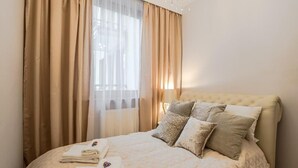 Ein ordentlich bezogenes Bett mit gesteppter Bettdecke, einem Kopfteil und mehreren Kissen.
