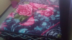 A bed with a floral bedspread, a headboard, and a nightstand with a lamp. - Rama Restaurant (Nairobi)