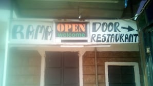 A building with a sign that reads "OPEN welcome" and "DOOR RESTAURANT" with arrows pointing to the entrance. - Rama Restaurant (Nairobi)