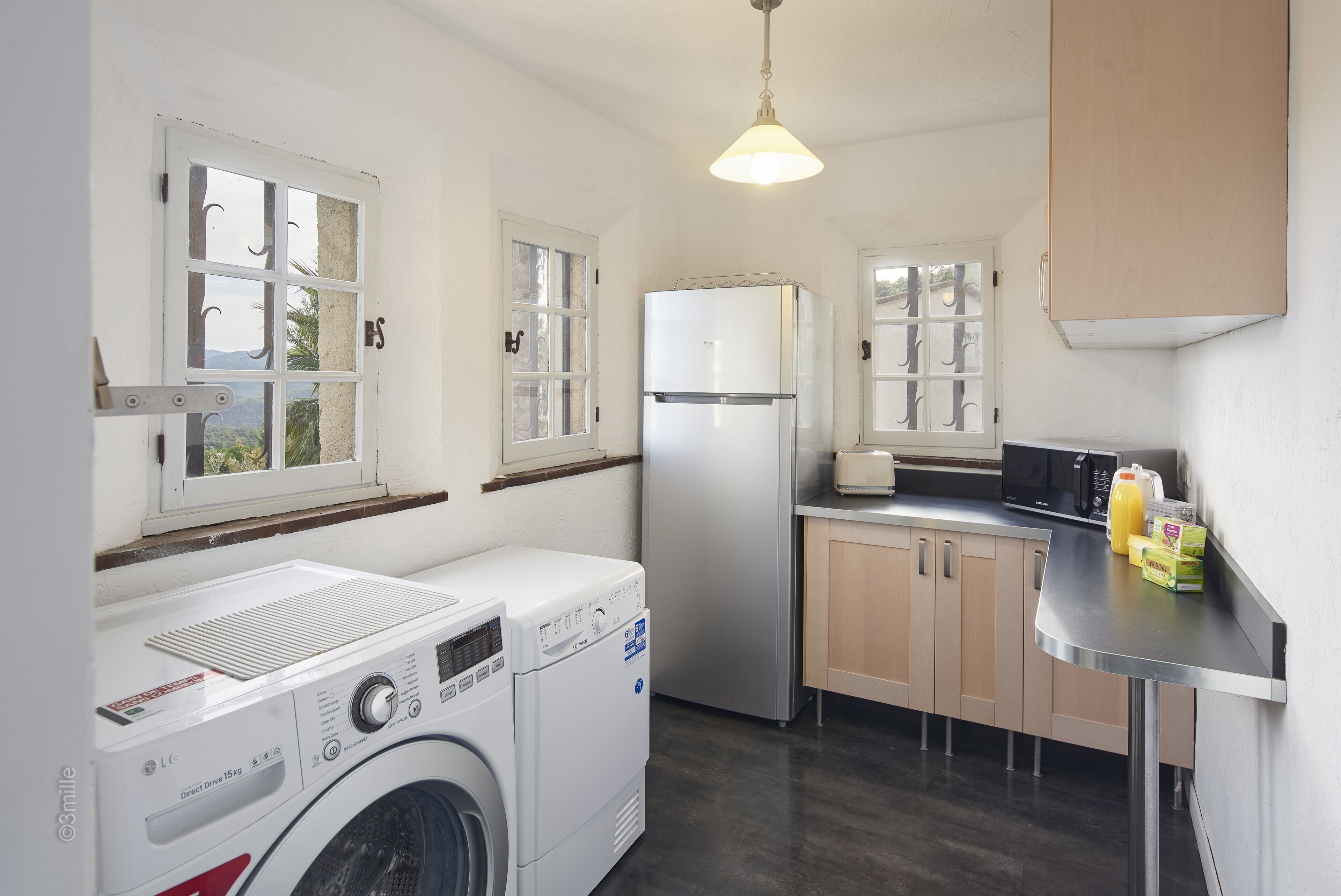 Una cocina compacta con lavadora, refrigerador y microondas.
