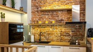 Eine moderne Küche mit einer Spritzschutzwand aus Ziegelsteinen, einer Holz Arbeitsplatte und Edelstahlgeräten.