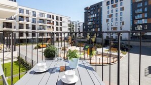 En balkong med ett bord dukat för två personer, med utsikt över en innergård med byggnader och en bil.