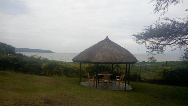 A thatched-roof gazebo with outdoor seating, overlooking a body of water and a distant island. - Homa Bay Tourist Hotel (Homa Bay)