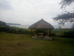 A thatched-roof gazebo with outdoor seating, overlooking a body of water and a distant island. - Homa Bay Tourist Hotel (Homa Bay)