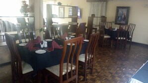 A dining area with wooden tables and chairs, a patterned floor, and a painting on the wall. - Homa Bay Tourist Hotel (Homa Bay)