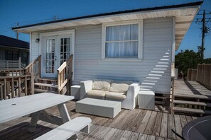 A white wooden house with a porch, a white sofa, and a small table.